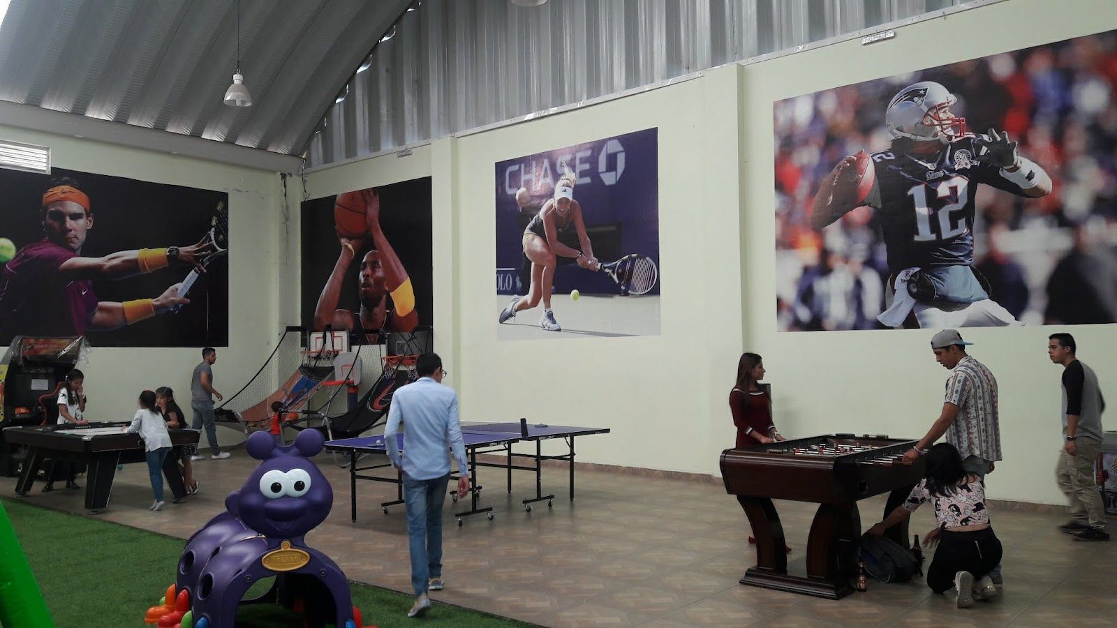 Área con futbolito, mesa de ping-pong y murales deportivos
