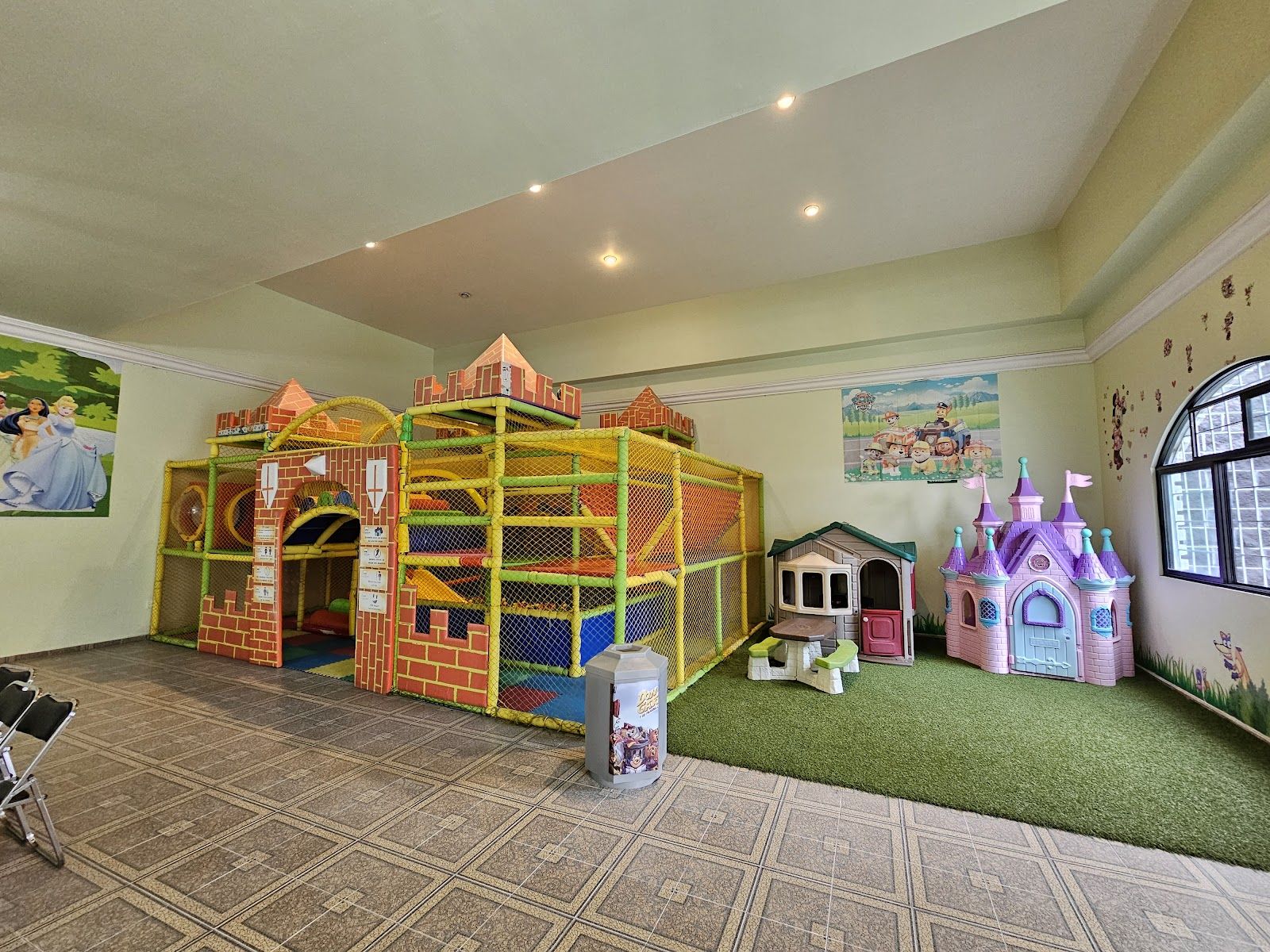 Área de juegos interior con castillo de princesas, casita y estructura de tubos